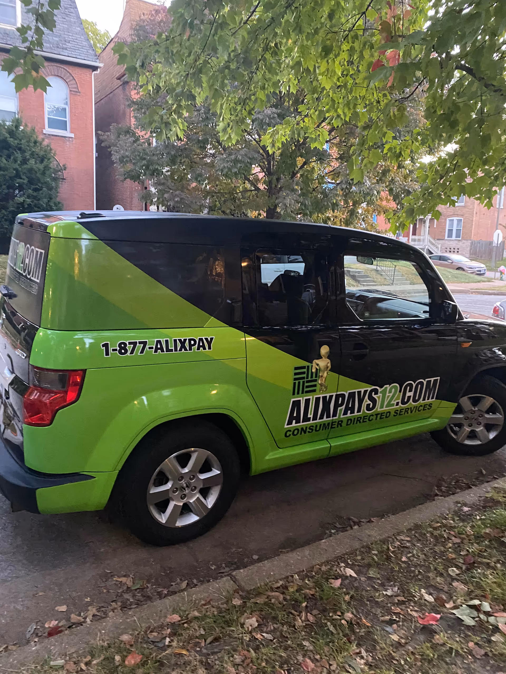Green AlixPay home health care van parked on a tree-lined residential street.