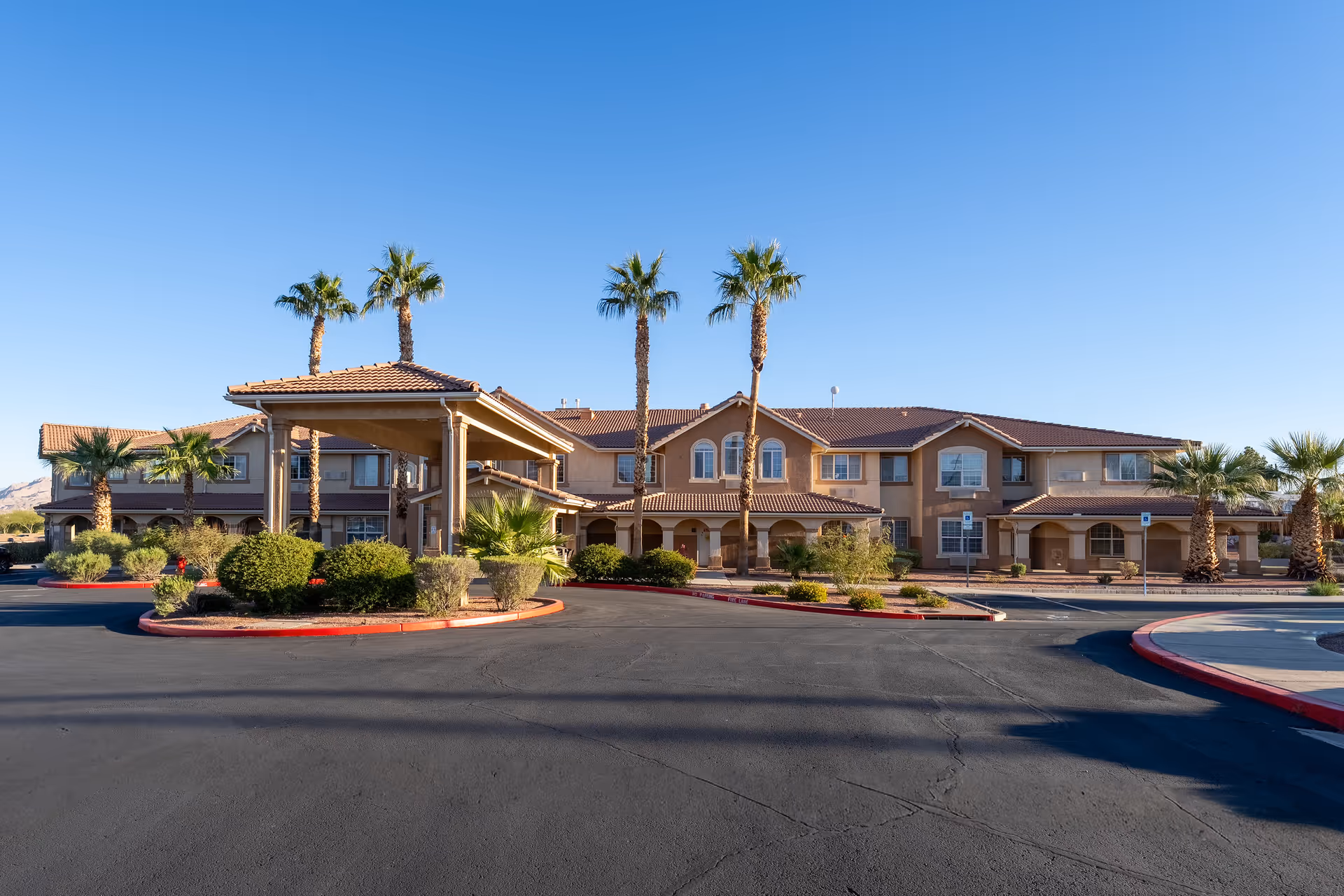 Sunlit exterior view of Parkway Assisted Living building with palm trees and entrance canopy.