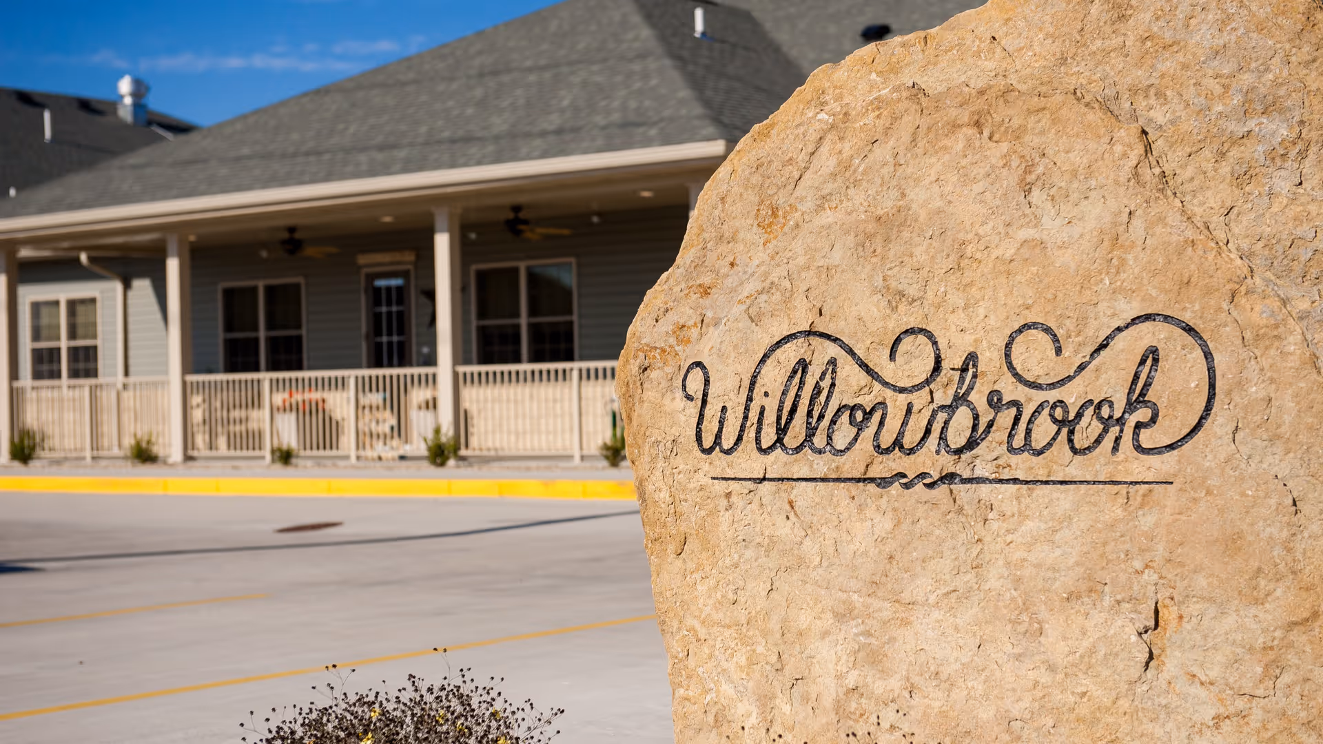 Large rock sign reading Willowbrook in front of a facility entrance.