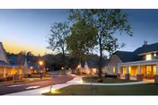 Exterior view of SunPorch of Dodge City showing lit walkways between residential buildings at dusk.