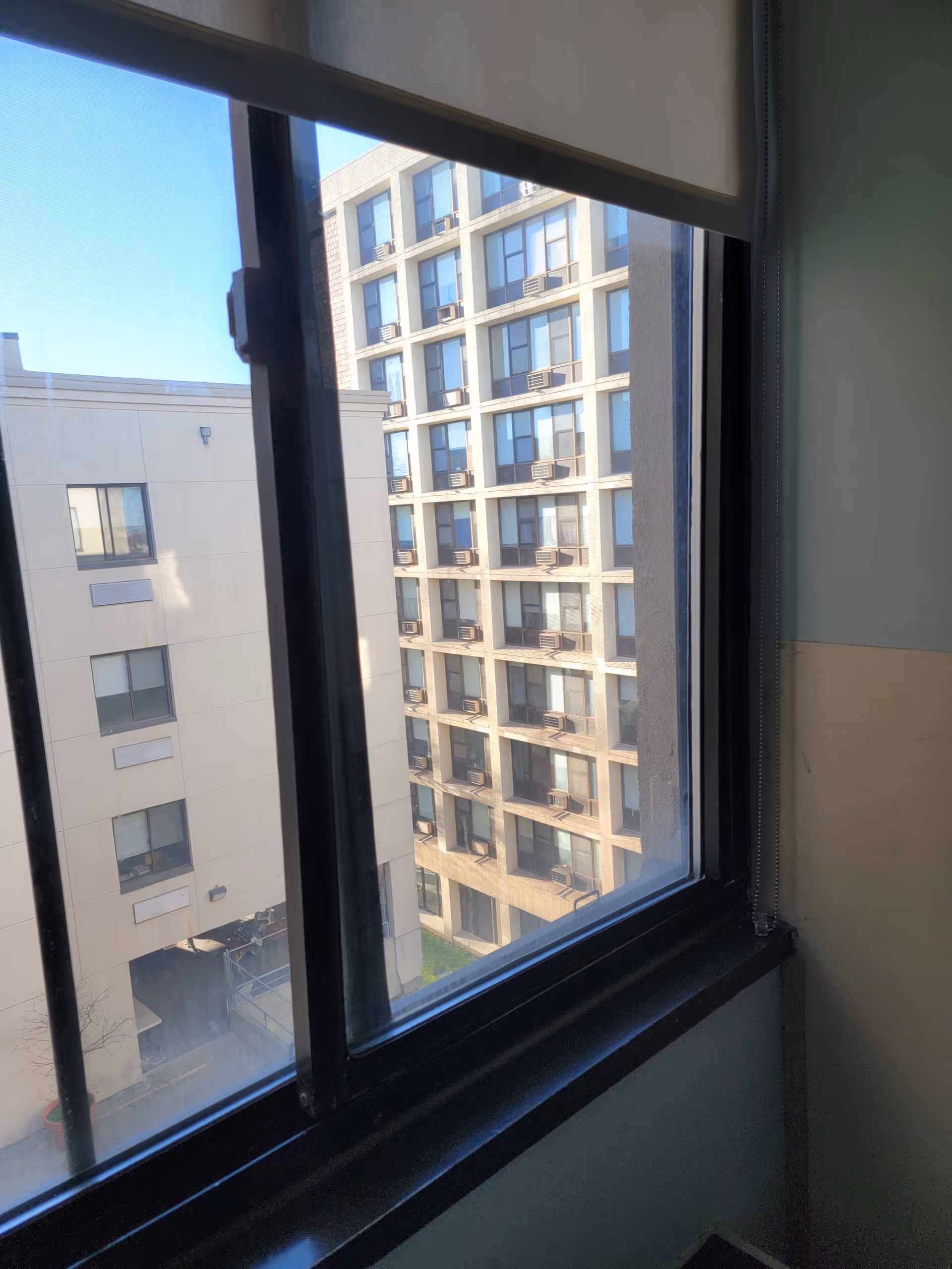 Interior window view overlooking a tall beige apartment building with balconies