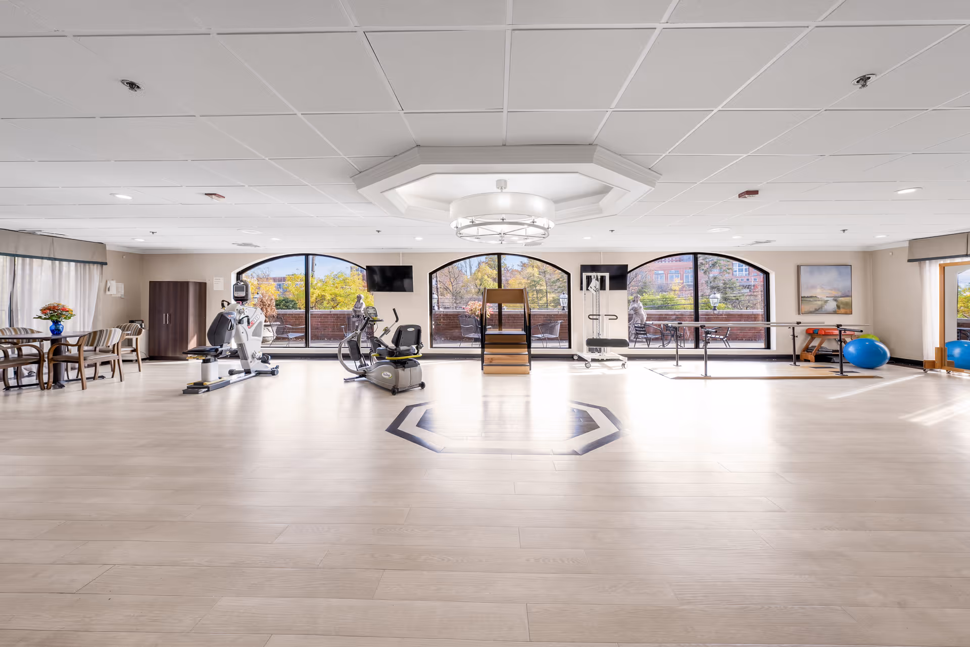 Spacious senior fitness center with cardio machines, balance equipment, and large windows.