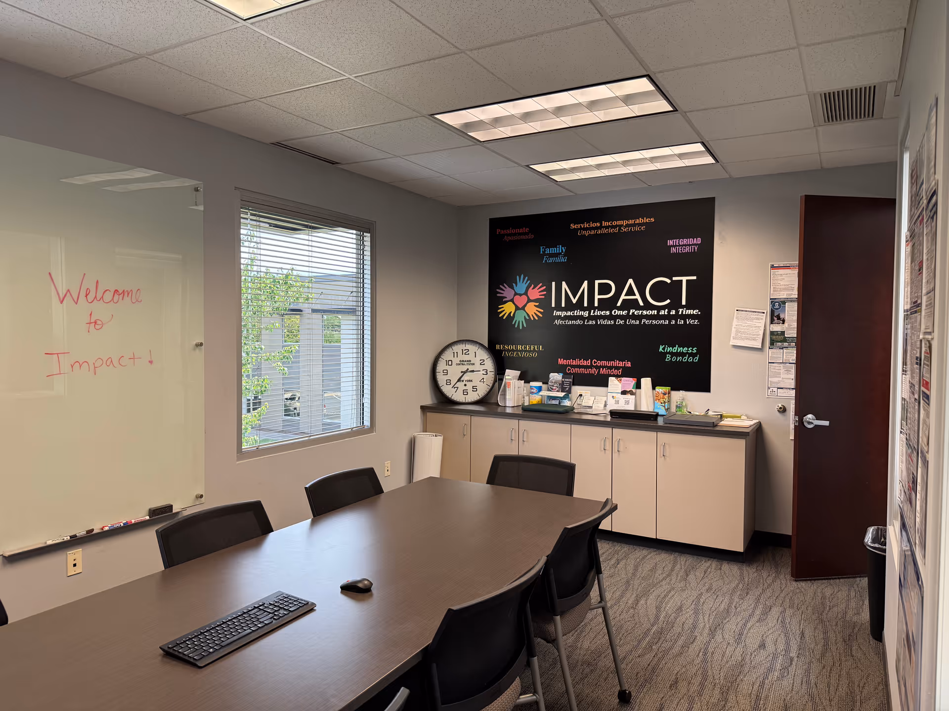 Conference room with a long table, chairs, a whiteboard, and IMPACT banner on the wall.
