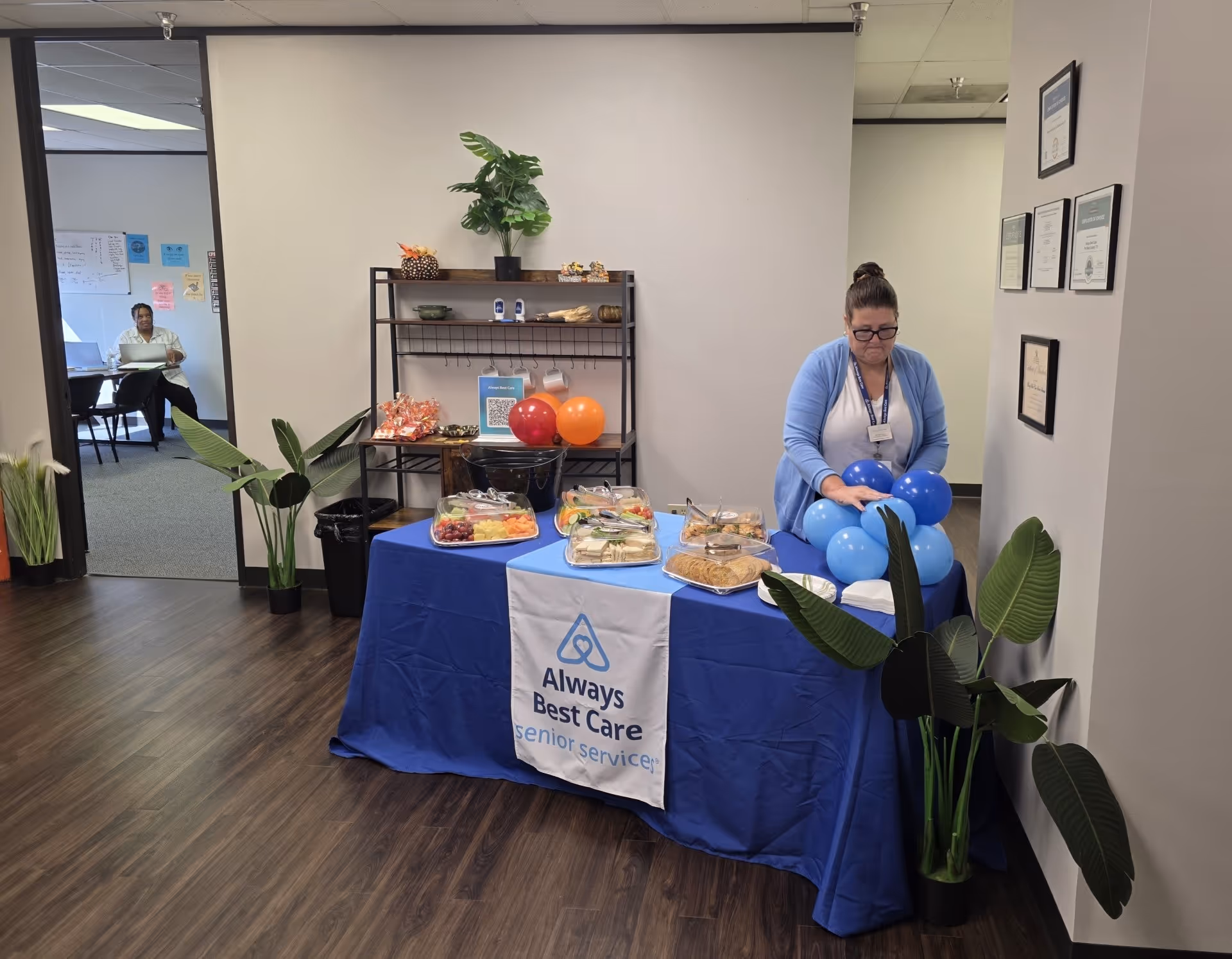 Staff arranges blue balloons beside a food table indoors at Always Best Care