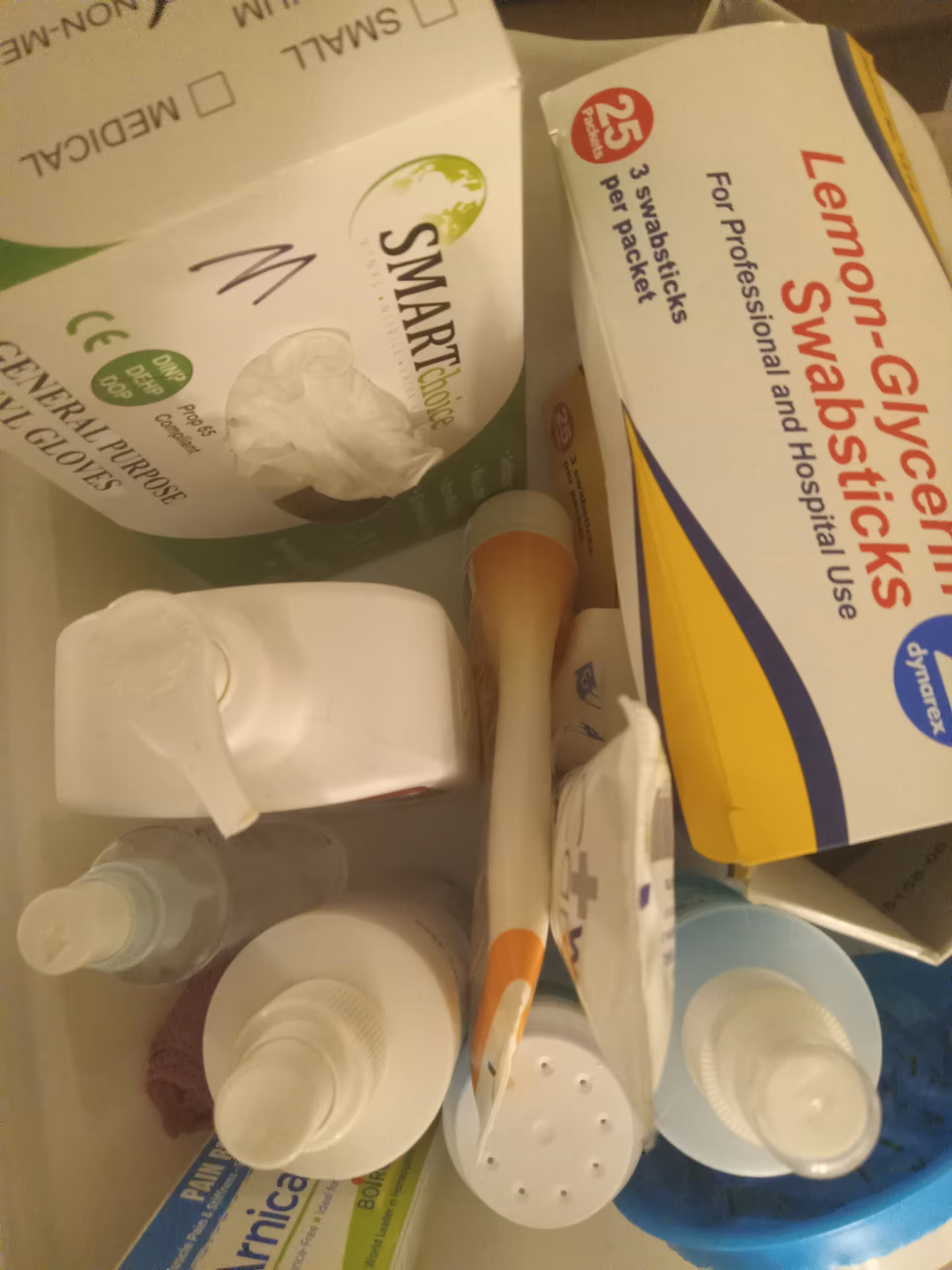 Close-up of bathroom items in a cabinet: toothbrush, toothpaste, sanitizer, and assorted boxes.