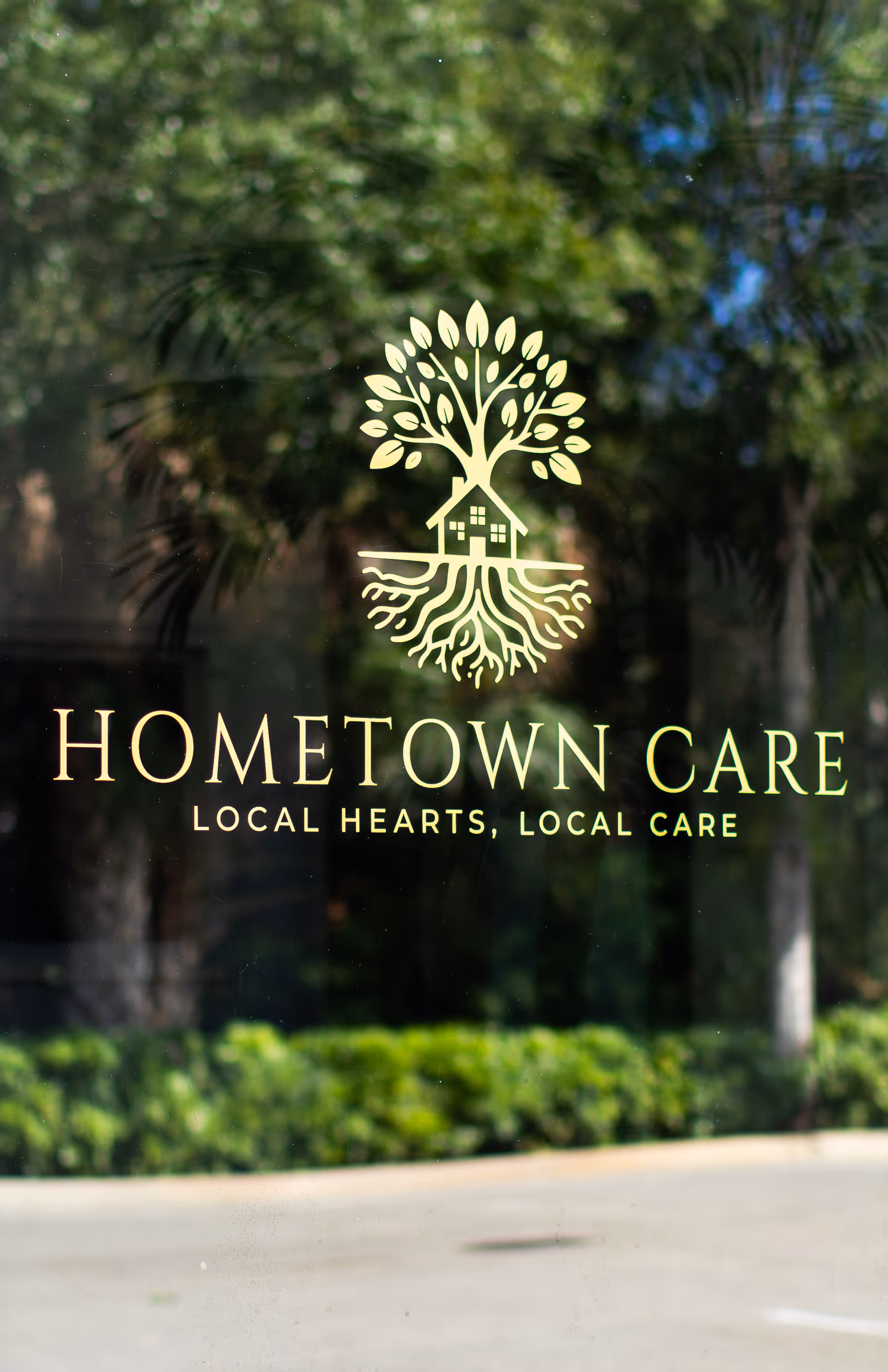 Glass door/window displays Hometown Care logo with trees reflected behind.