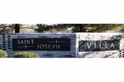 Outdoor stone sign reading Saint Joseph Villa, surrounded by trees.