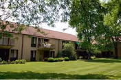 Exterior view of a Dunwoody Village senior living building with lawn and trees.