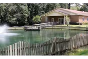 Exterior view of Suwannee Valley Nursing Center beside a pond with a wooden fence.