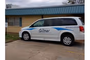White Gilmer Nursing and Rehabilitation van parked in front of a single-story building.