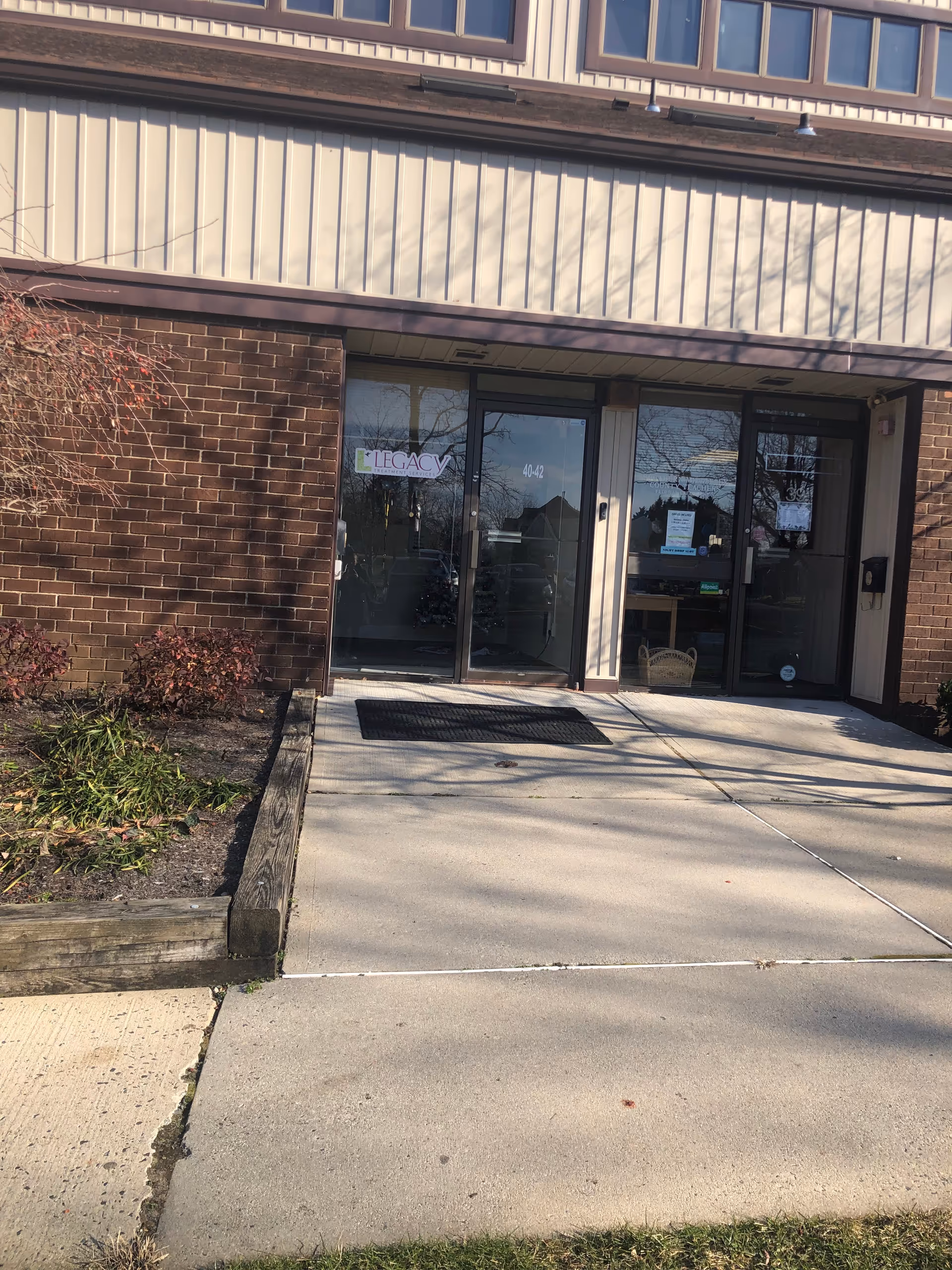 Front entrance of a brick building with glass doors and a LEGACY sign