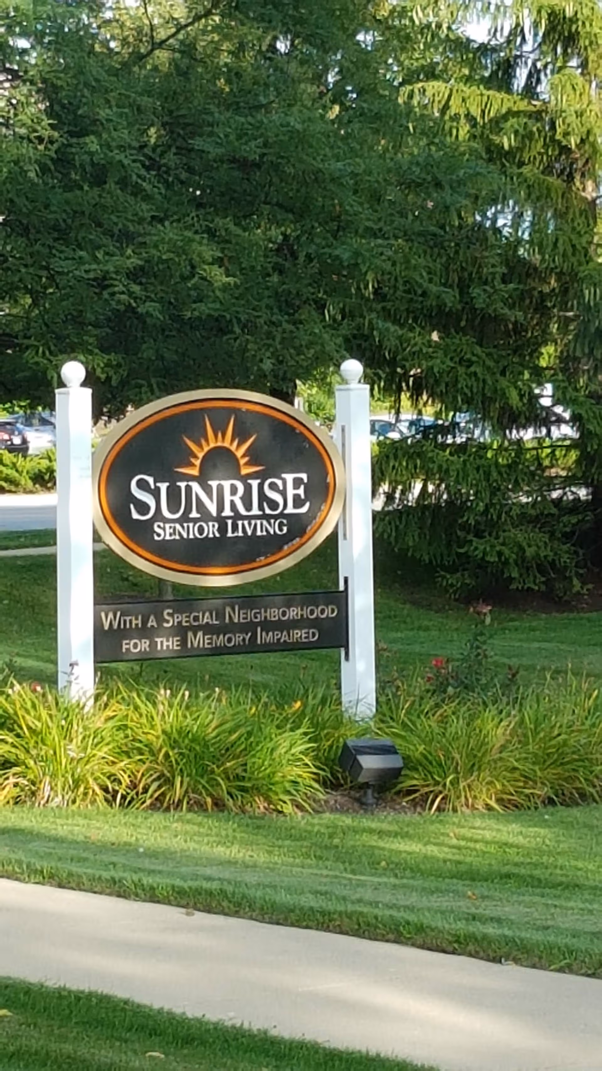 Sunrise Senior Living entrance sign amid green landscaping and trees.