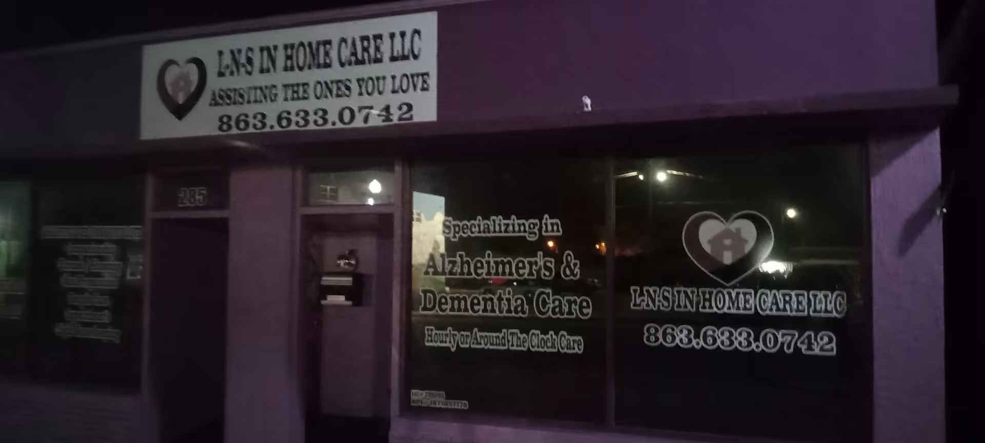 Purple storefront at night displaying LNS In Home Care LLC and dementia care advertisements.