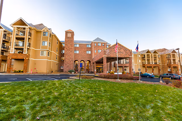 Exterior view of Brookdale Wornall Place with a brick entrance, flags, and a grassy lawn.