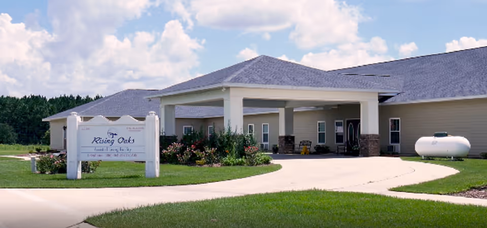 Front view of Rising Oaks Assisted Living facility with a circular driveway and landscaped entry.