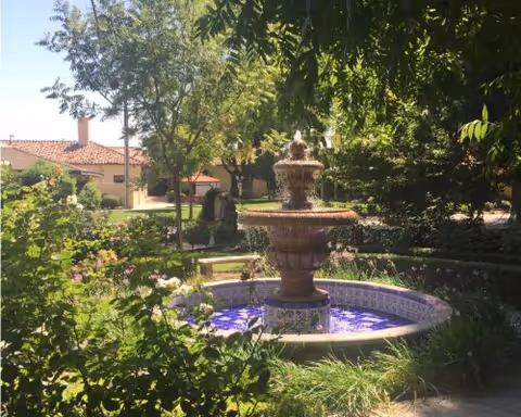 Outdoor garden courtyard with a decorative fountain and lush greenery.