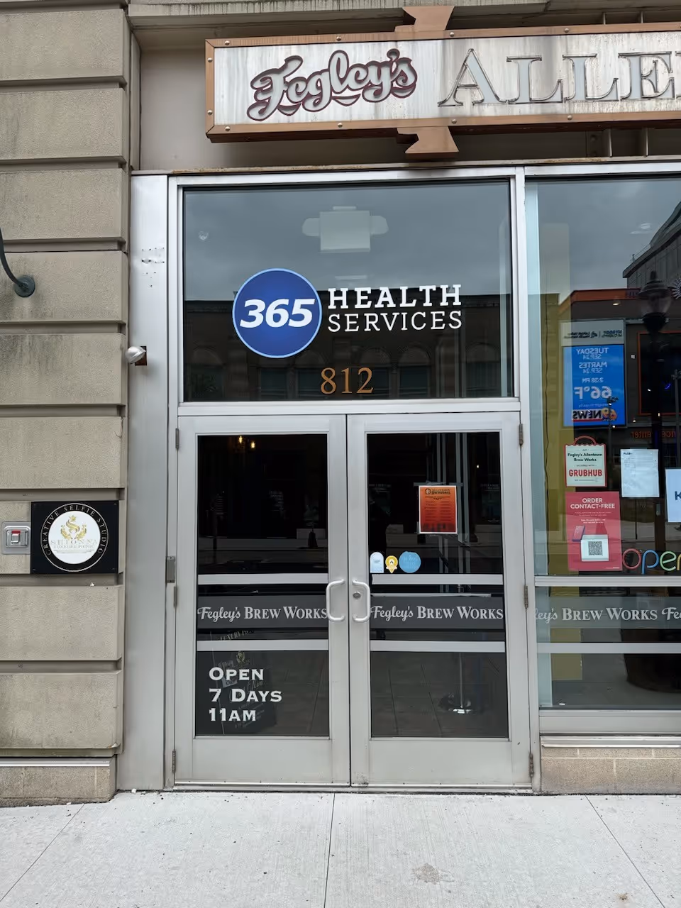 Storefront with 365 Health Services sign and glass entrance door.