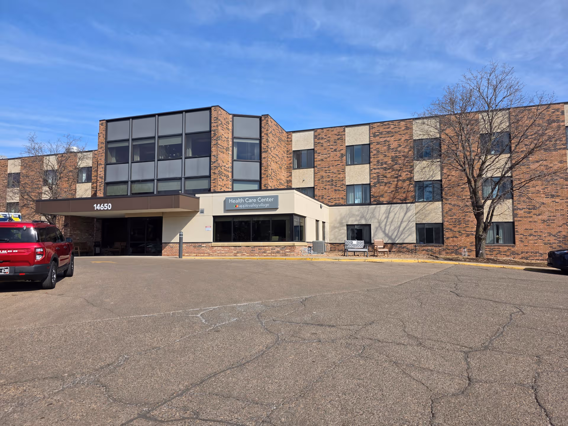 Exterior view of Apple Valley Village Health Care Center building with parking lot.