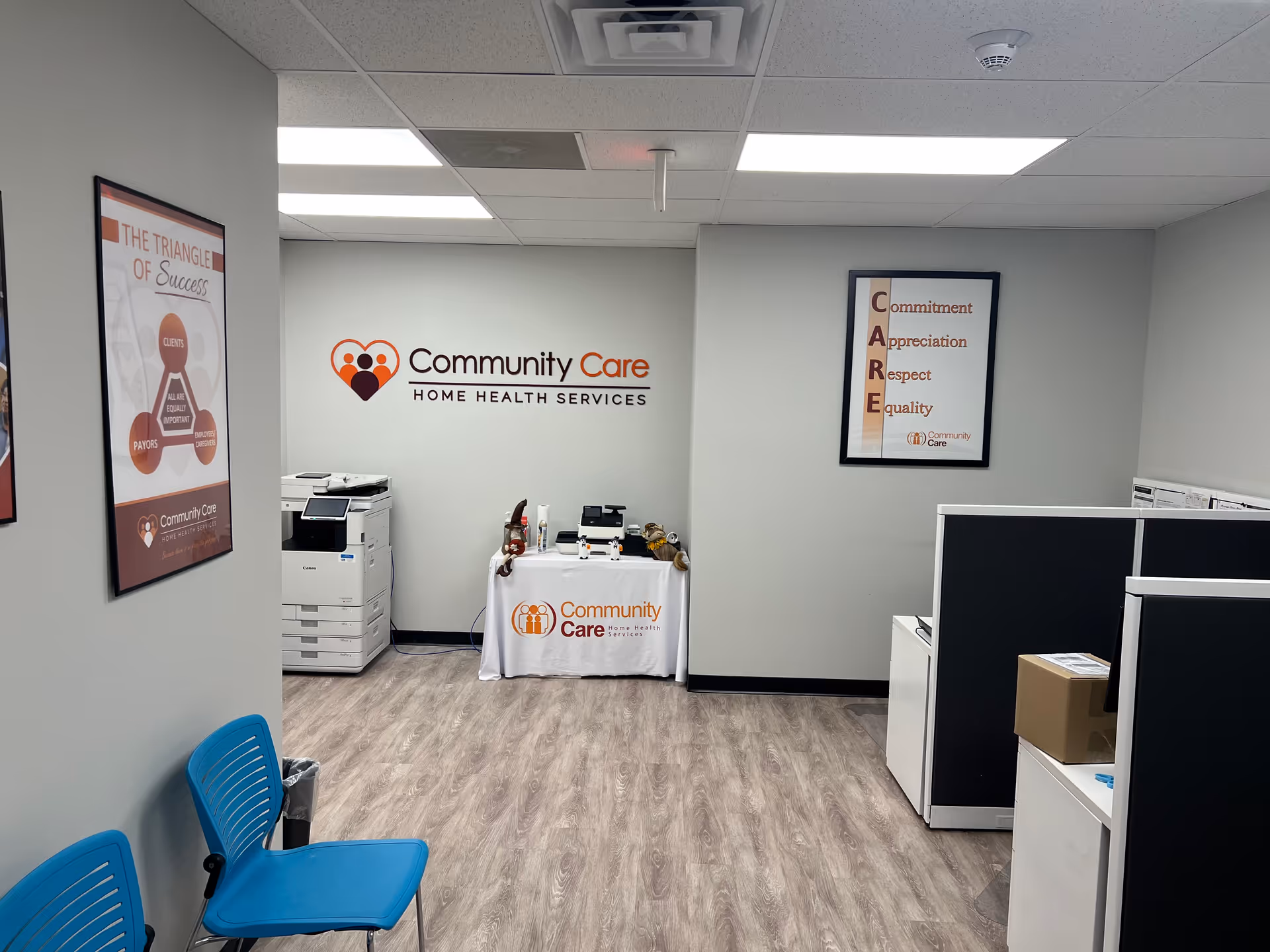 Reception area of Community Care Home Health Services with logo, cubicles, and blue chairs.