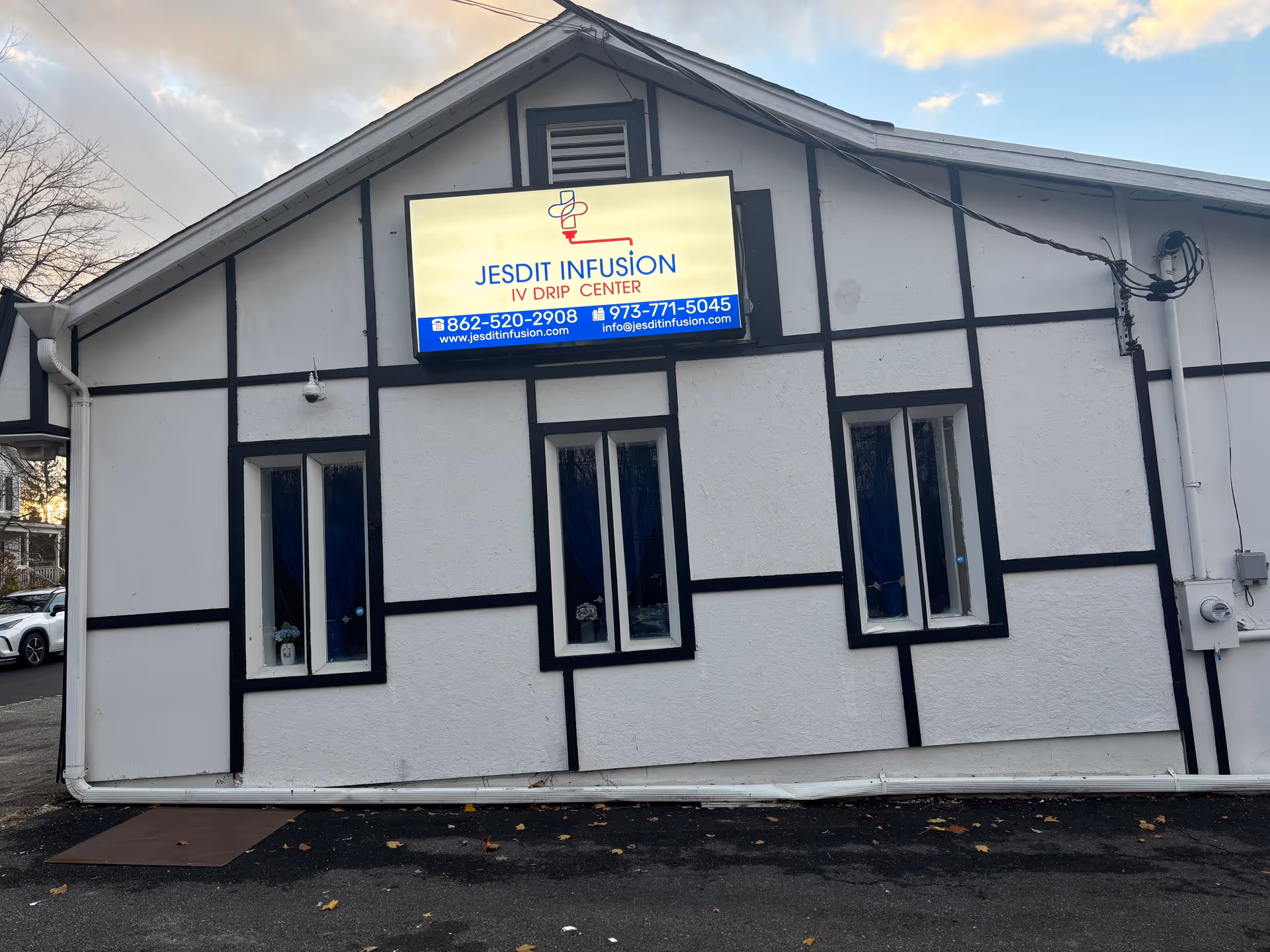 Exterior view of a white building with black trim and a Jesdit Infusion Drip Center sign.