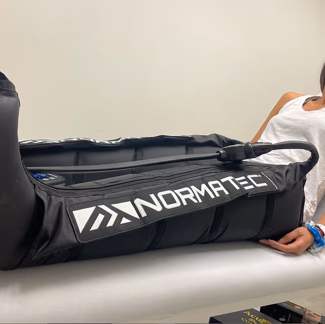 Person on therapy table wearing Normatec leg compression sleeves.
