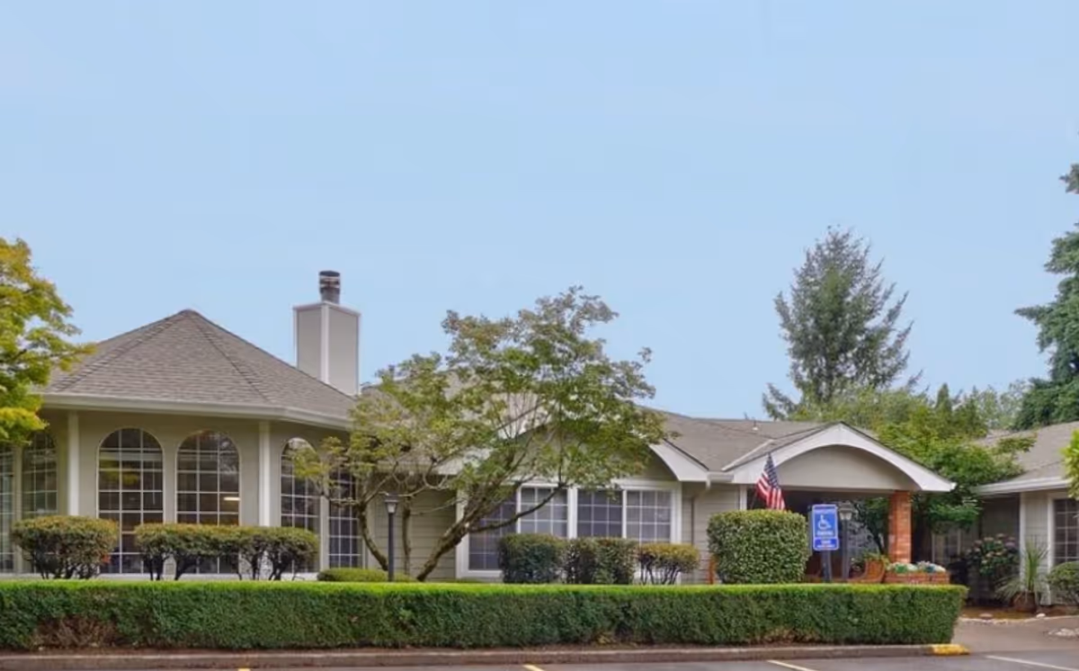 Regency Woodland senior living building exterior with trimmed hedges and a welcoming entrance.
