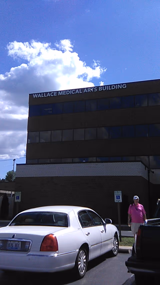 A white sedan parked in front of a multi-story building with a Wallace Medical Arts sign.