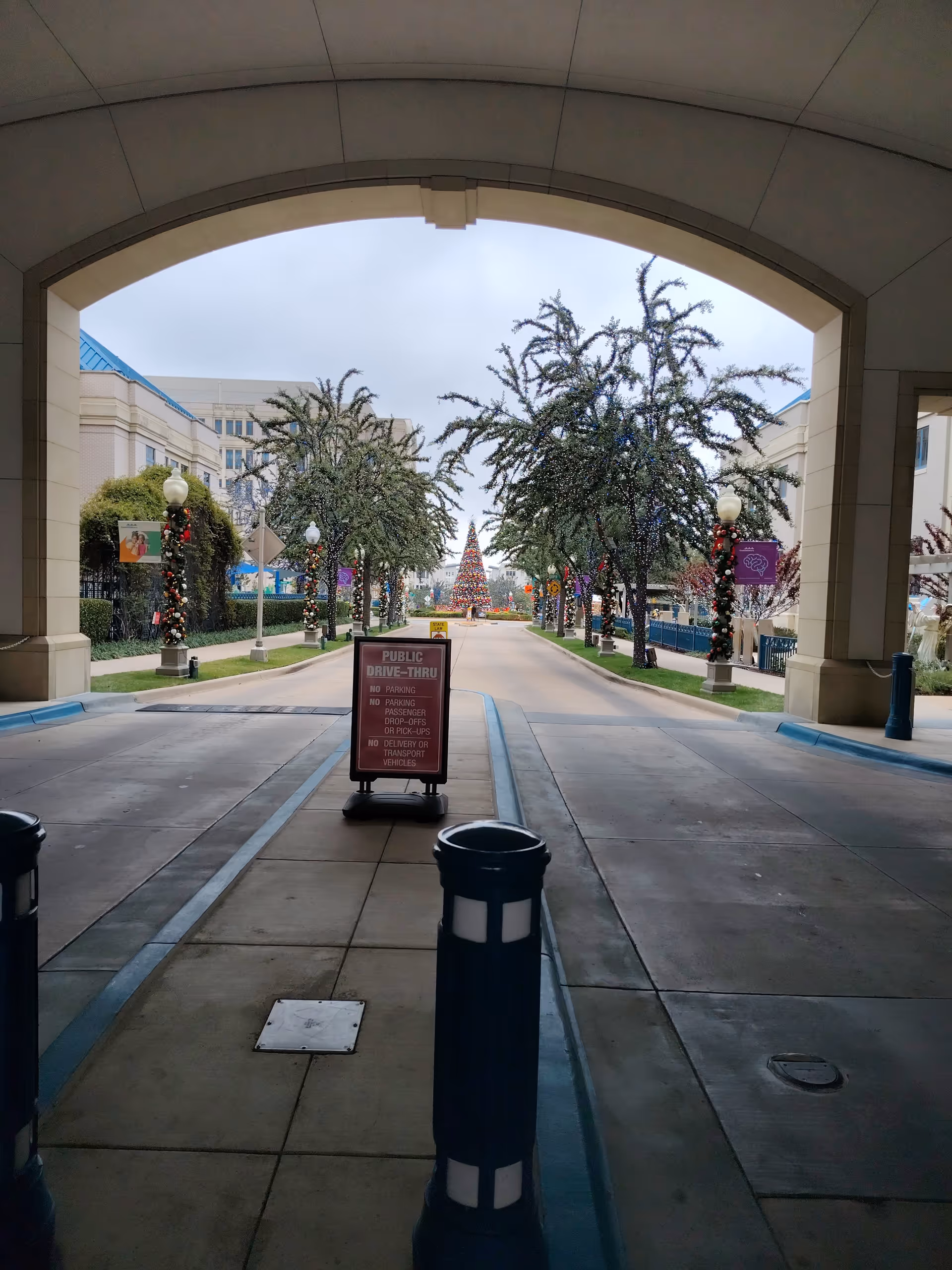 Covered outdoor archway opens to a decorated courtyard with trees and festive lighting.
