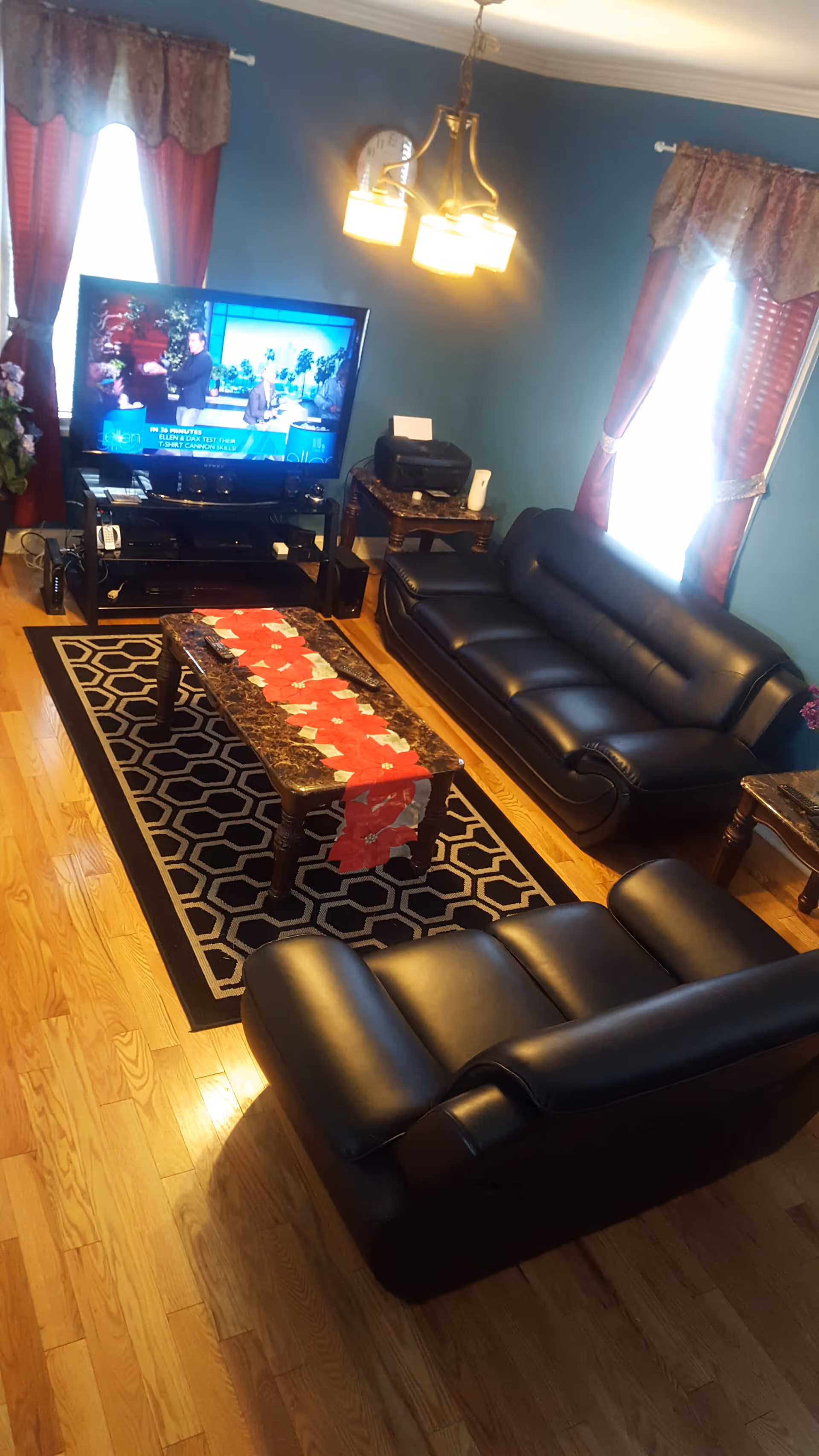 A cozy living room with black leather sofas, a coffee table, rug, and TV.