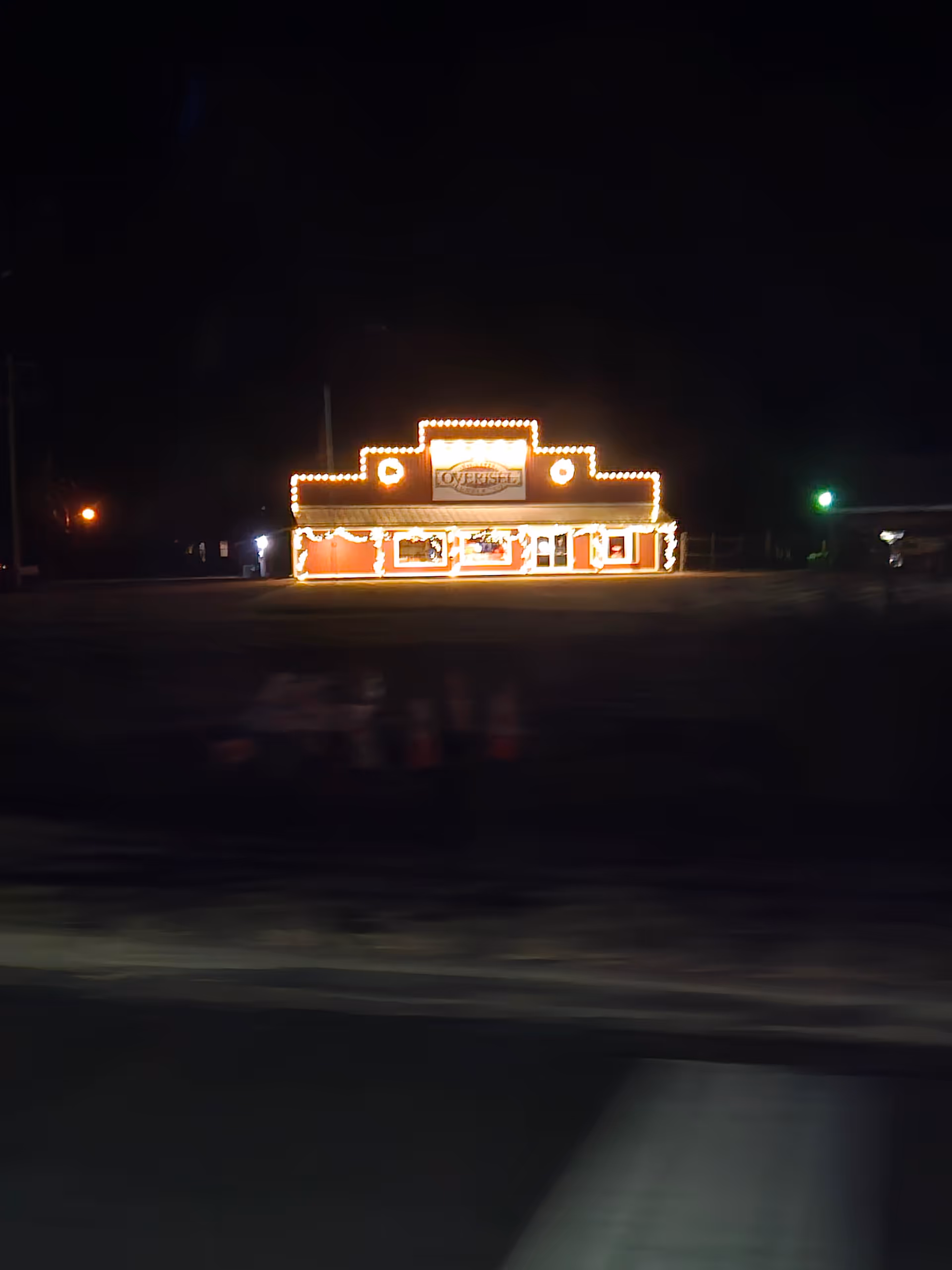 Nighttime exterior view of a building with bright marquee-style lights outlining the front.