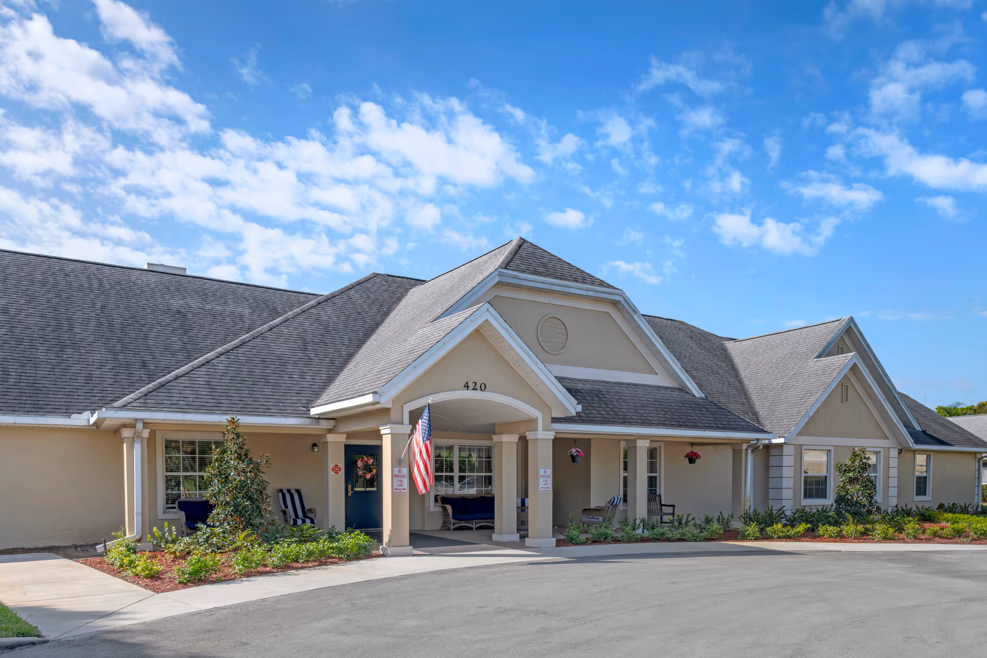 Front view of a memory care facility with a covered entrance and flag.