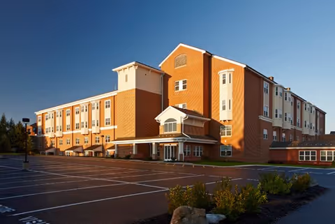 A brick senior living facility with a prominent entrance and empty parking.