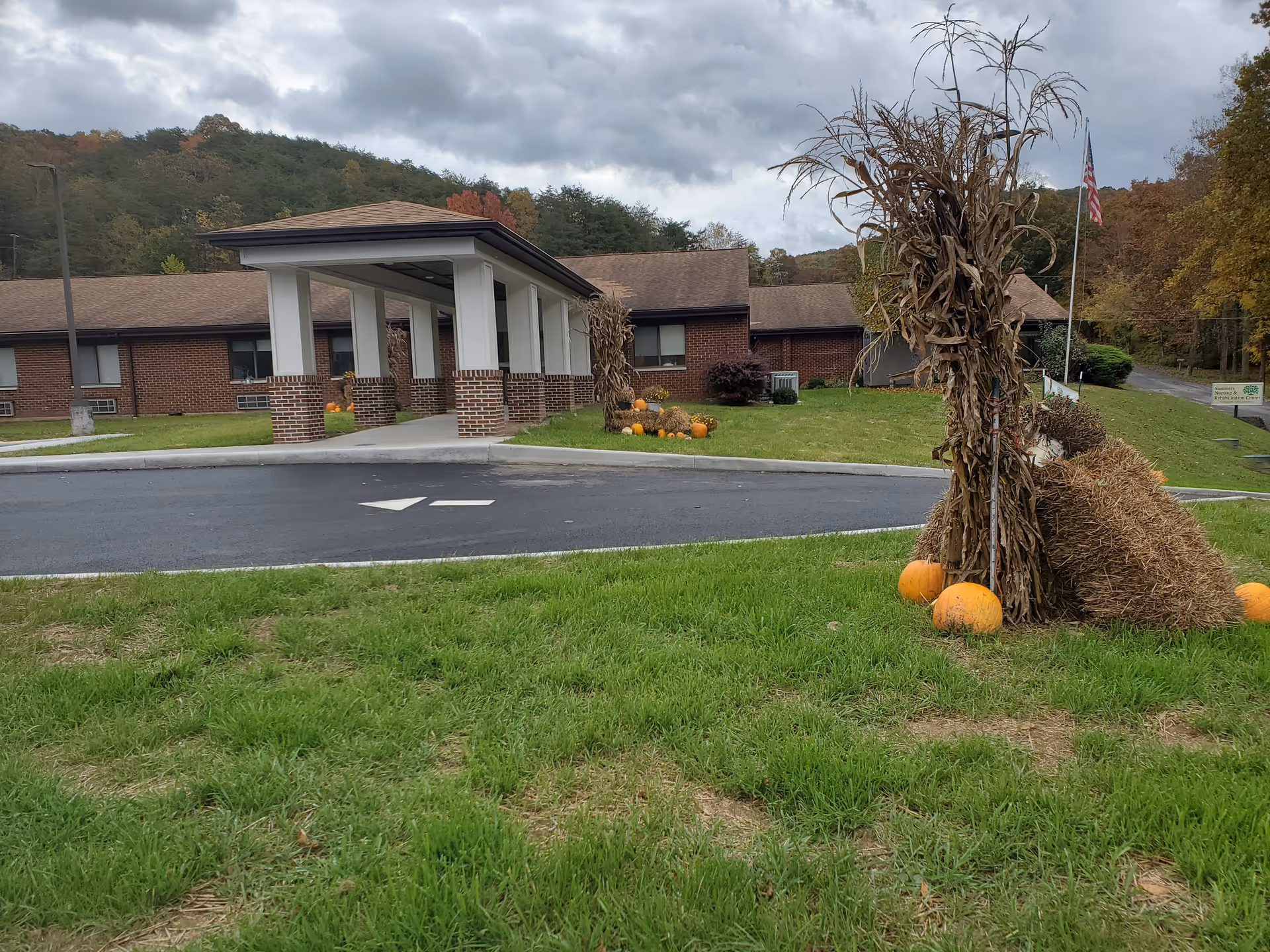 Exterior view of Summers Healthcare Center with brick entrance, pumpkins, and fall decorations.