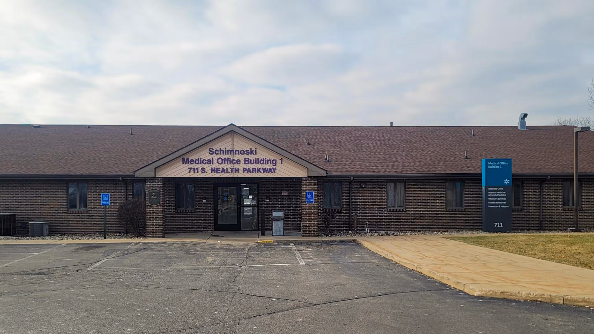 Exterior of a brick medical office building with a front entrance and parking lot.