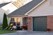 A brick-and-siding senior living villa with a green garage door and potted flowers.