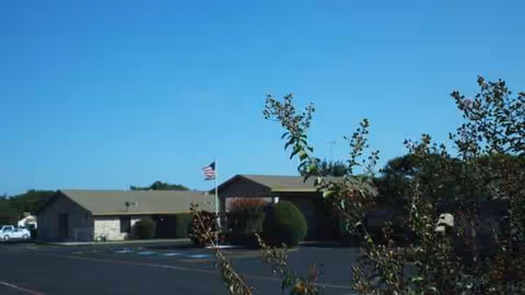 Granbury Care Center exterior building with parking lot and American flag in foreground.
