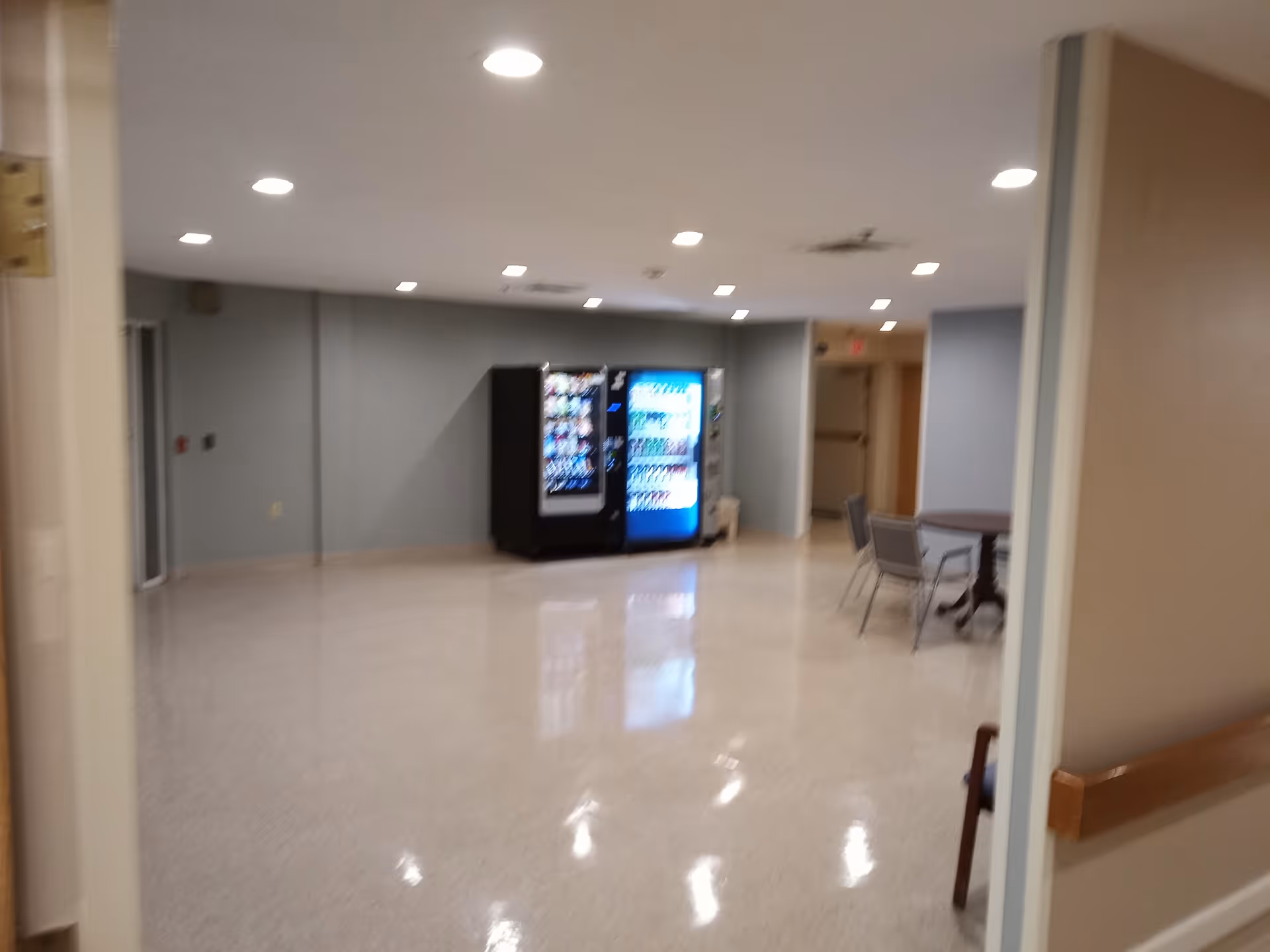 Interior hallway of a senior living facility with vending machines and a seating area.