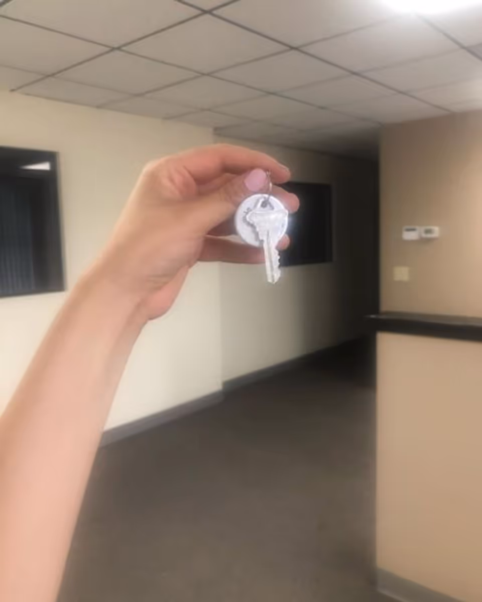 Person's hand holds two keys in a hallway of a senior living facility.