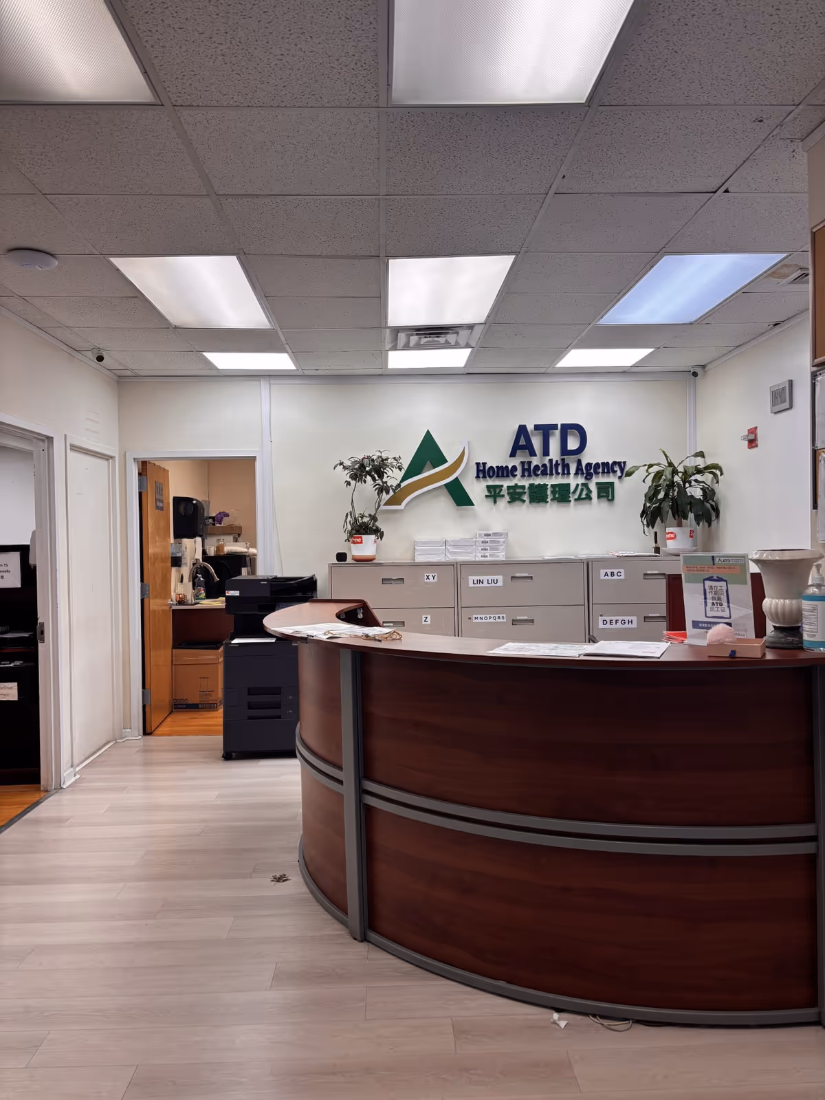 ATD Home Health Agency lobby with curved reception desk, filing cabinets, and plants.