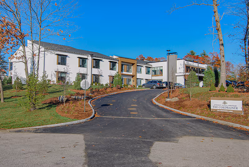Exterior view of The Cordwainer senior living campus with driveway and landscaped grounds.