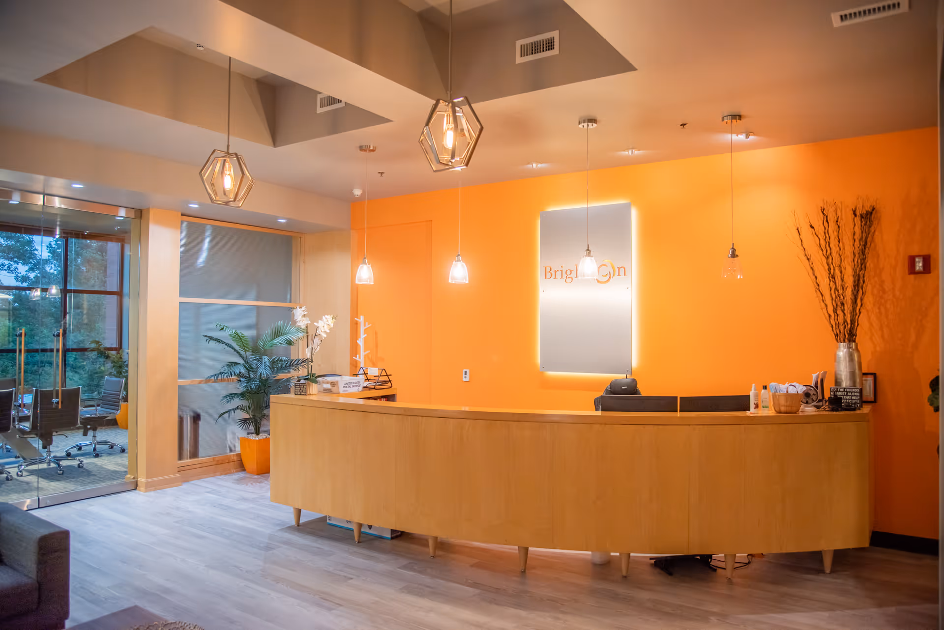 Bright orange lobby with curved reception desk and pendant lights.