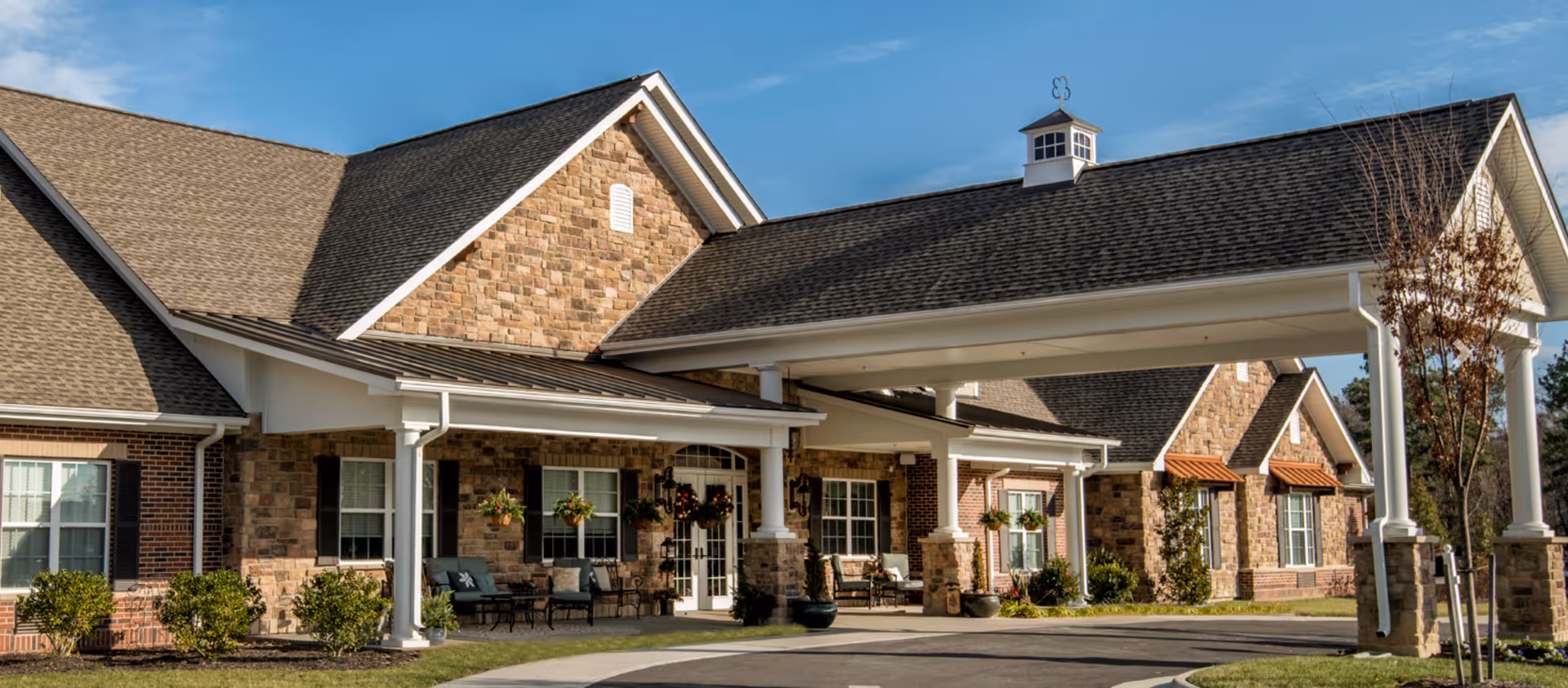 Exterior view of Bickford of Chesterfield with a brick facade, covered entrance, and outdoor seating.