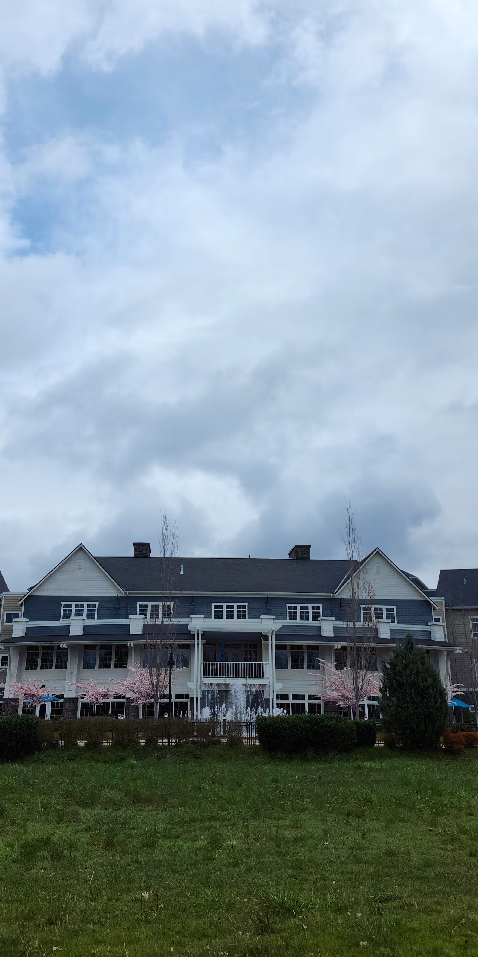 Waterford Grand exterior building with a central fountain and pink blossom trees in front lawn