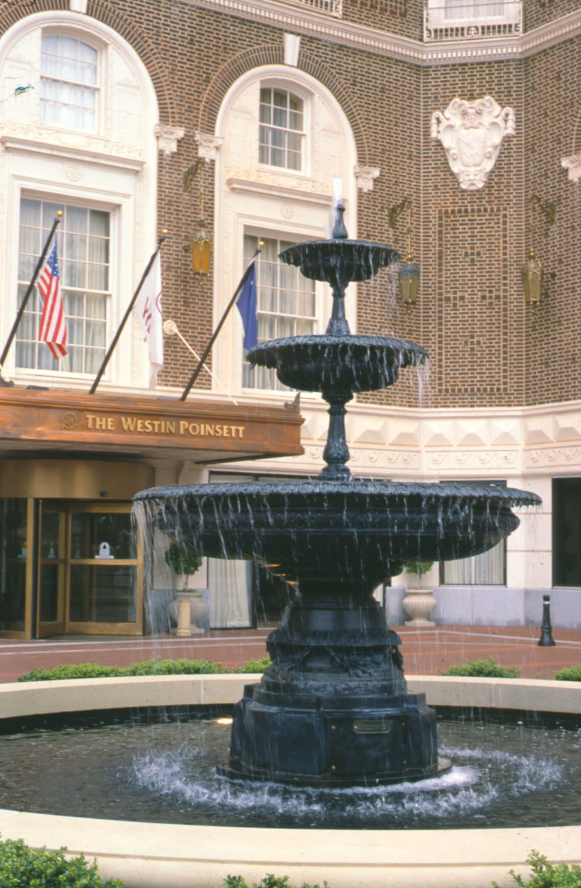 Front entrance of The Westin Poinsett with a tiered fountain and flags.