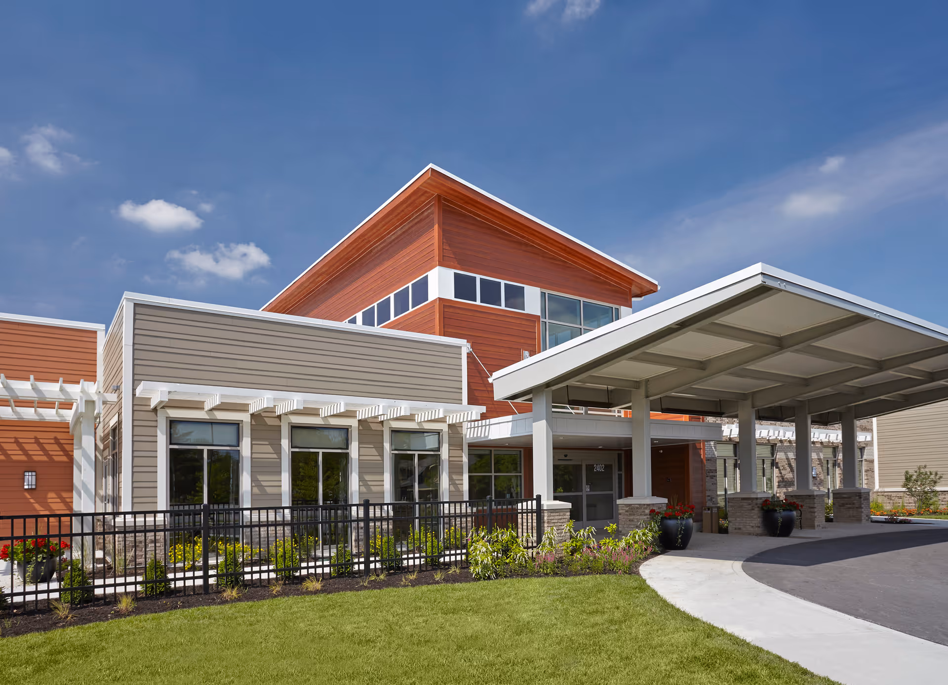 Modern senior living facility exterior with a covered entrance and landscaped front yard.