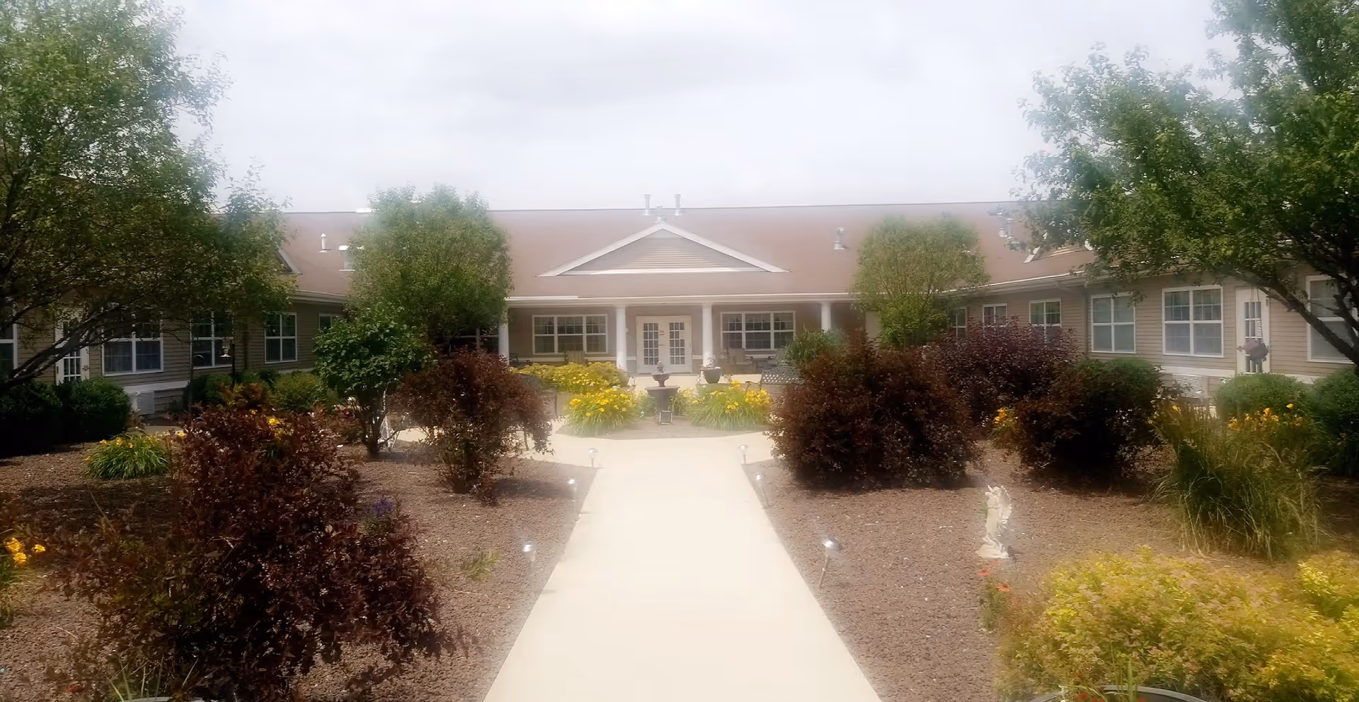 Front view of The Pointe at Pontiac building with walkway and landscaped garden.
