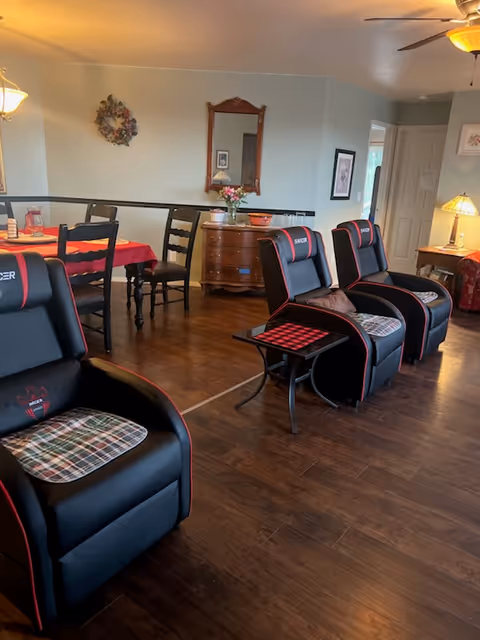 Common living area with black and red recliner chairs, dining table, and decor.