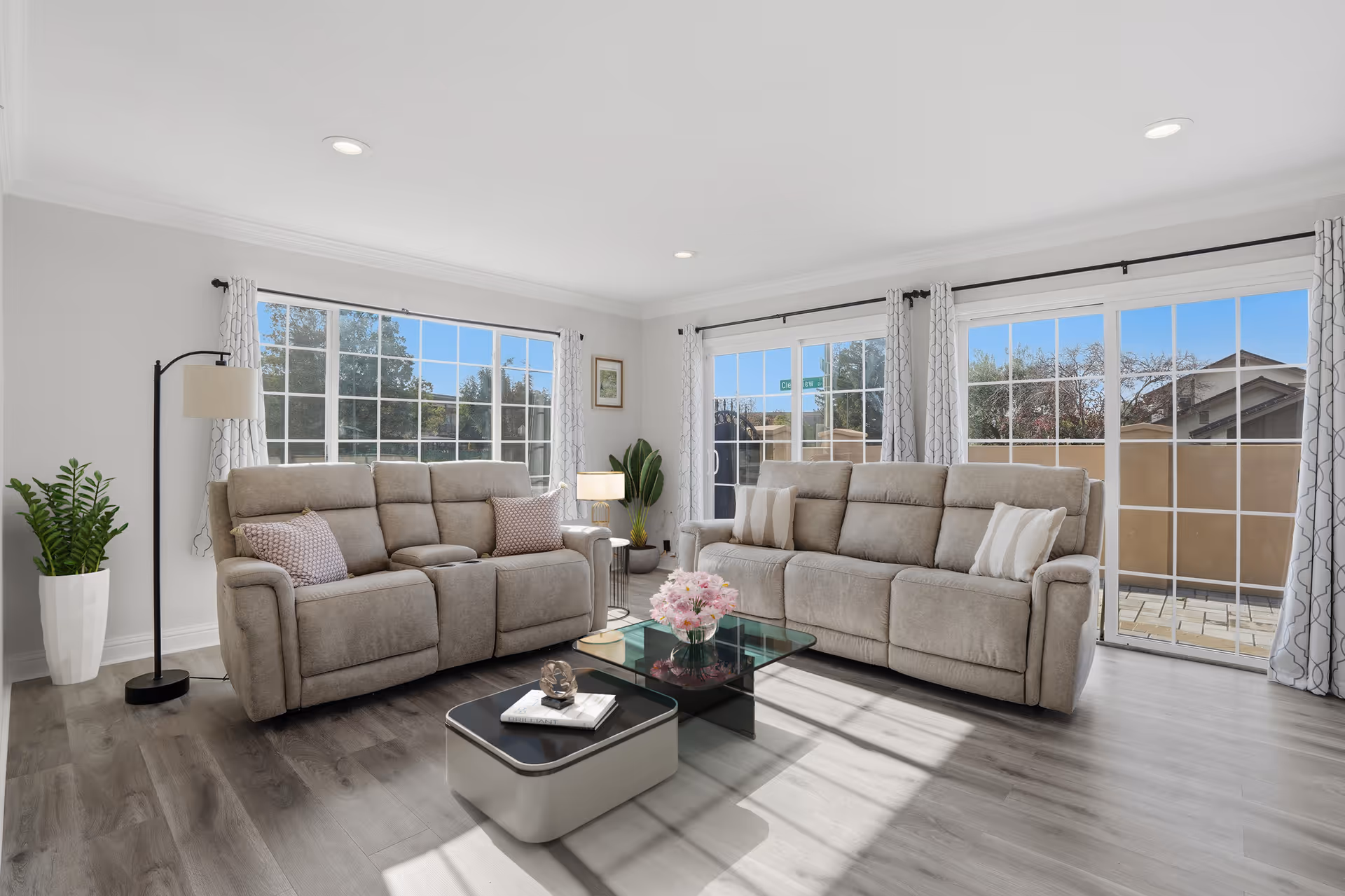Bright living room in a senior facility with beige furniture and large windows.