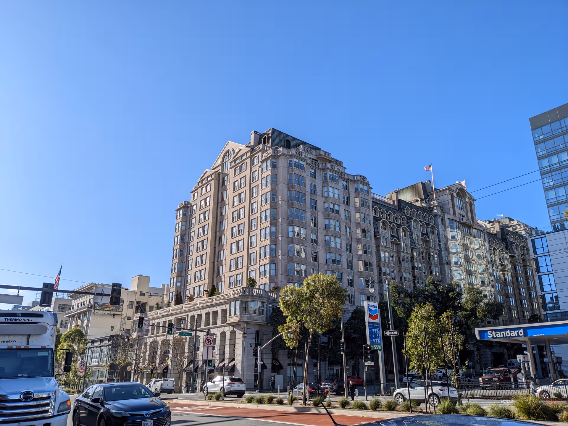 Tall multi-story building along a city street under a clear blue sky.