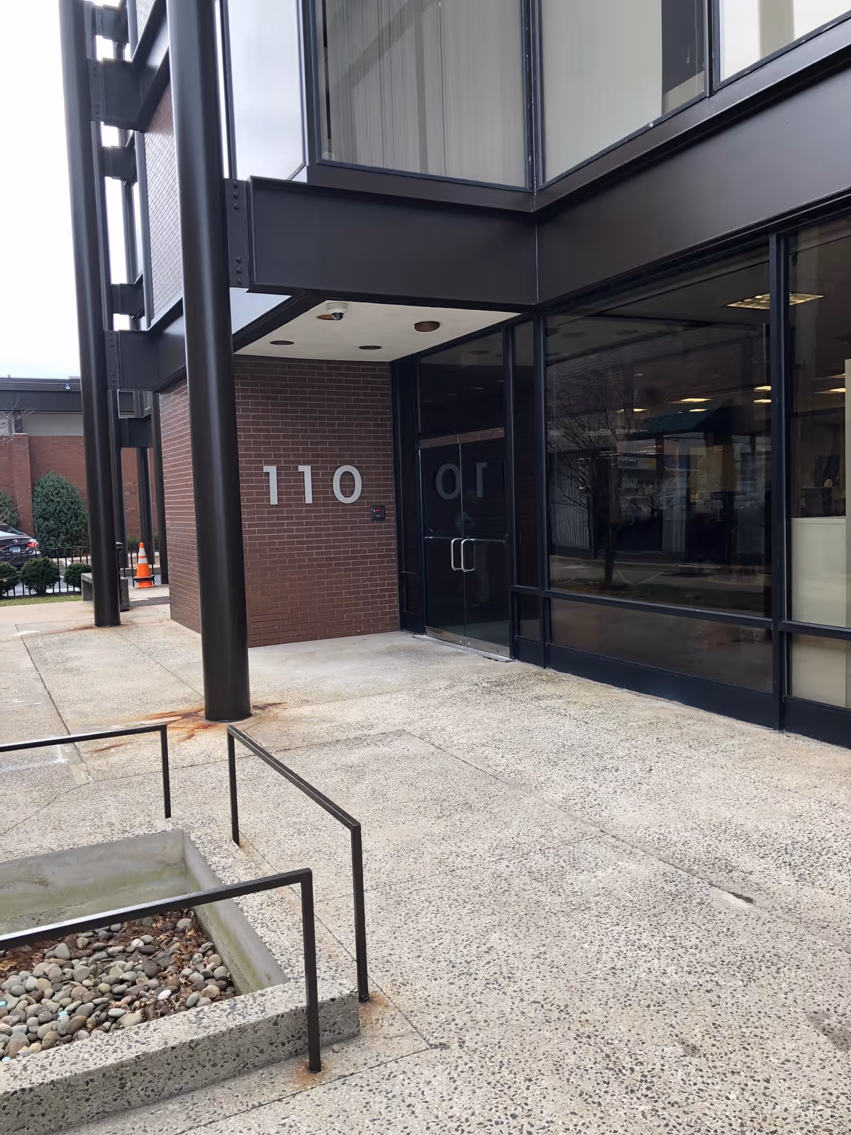 Exterior entrance to Compassionate Care At Home with glass doors and brick wall.